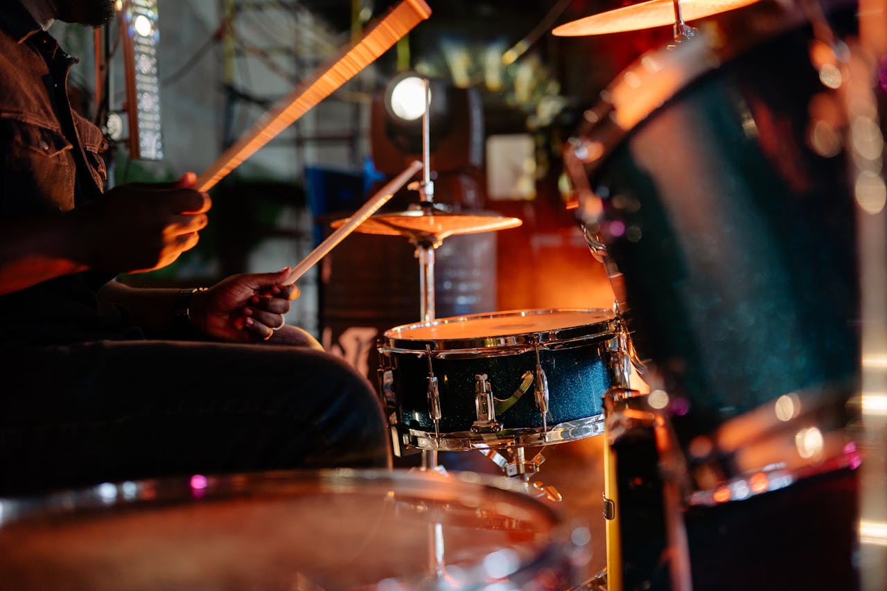 Musician performing a live drum solo during a vibrant indoor concert.